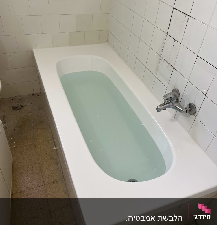 אמבטיה מלאה במים עם חיפוי אריחים לבנים